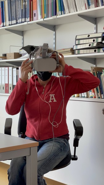 Eine Frau schaut einen Film mit einer VR-Brille. Sie trägt eine Maske.