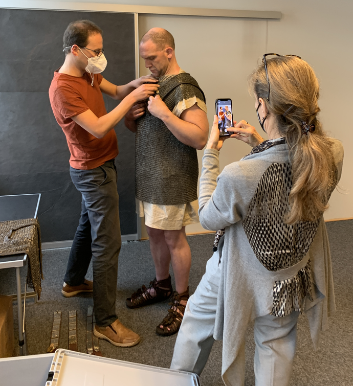 Matthias hilft unserem Schauspieler beim Anziehen des Kettenhemdes. Foto: Altertumskommission/Reck.